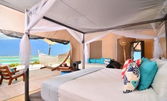 a bed with a canopy is in a room with a view of the ocean at Anegada Beach Club