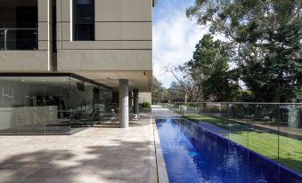a modern house with a large blue swimming pool surrounded by grass and trees , creating a serene and inviting atmosphere at Knightsbridge Canberra