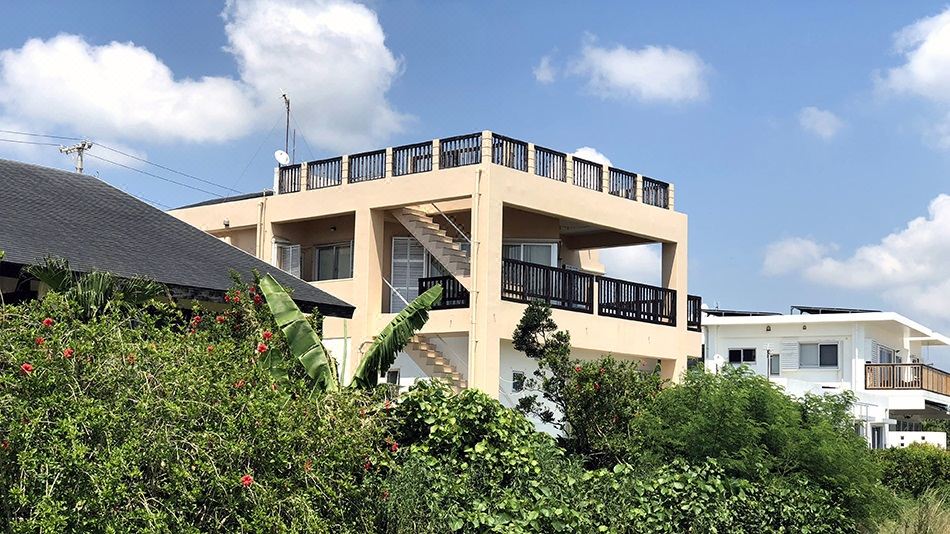 a three - story building with a balcony and stairs leading up to it , surrounded by trees at Pontoon