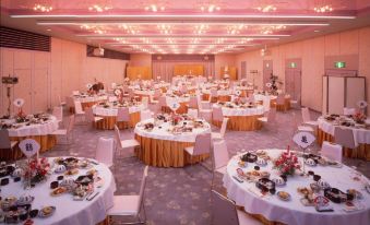 a large banquet hall with multiple round tables covered in white tablecloths and set for a formal event at Todaya