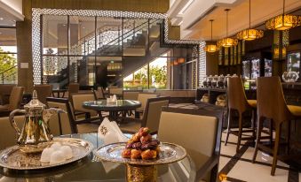a restaurant with a glass table and chairs , as well as a staircase in the background at Ayla Grand Hotel Al Ain