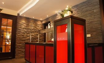 a modern hotel reception area with a red counter and stone wall , giving it an elegant and stylish appearance at Moselhotel & Restaurant Zur Traube Gmbh