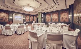 a large dining room with round tables covered in white tablecloths and chairs arranged around them at Hotel Nassauer Hof