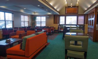 a dining room with several tables and chairs , as well as a bar area in the background at Residence Inn Harrisburg Carlisle