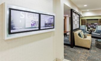 a hotel lobby with a television mounted on the wall and a couch in the background at SpringHill Suites Minneapolis Eden Prairie