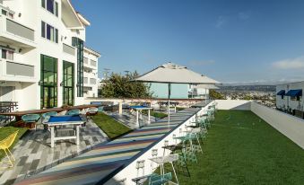 a large outdoor patio area with several chairs , tables , and umbrellas , surrounded by a grassy area at Hotel Hermosa