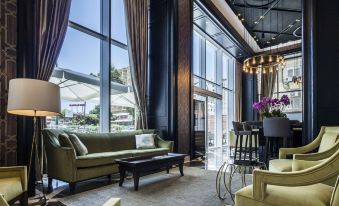 a modern living room with large windows , green sofas , and a bar area , surrounded by chairs and tables at David Tower Hotel Netanya by Prima Hotels - 16 Plus