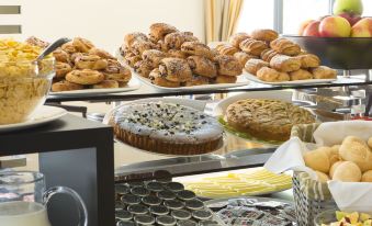 a display case filled with various types of pastries , including cakes and croissants , in various flavors at Maranello Palace Hotel