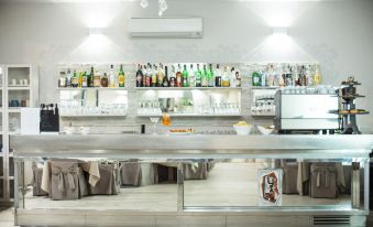 a well - equipped bar with various bottles and glasses on display , along with a dining table in the background at Hotel Europa