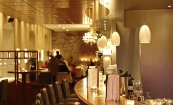 a bar with a marble counter and chairs , along with a chandelier hanging from the ceiling at Hotel des Balances