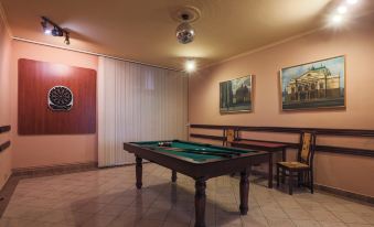 a billiards table is set up in a room with a couch and chairs , and paintings on the wall at Hotel Victoria