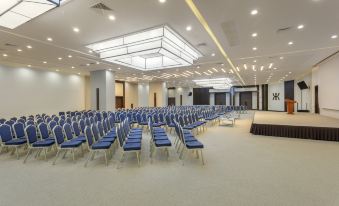 a large , empty conference room with rows of blue chairs and a stage at the front at Kefaluka Resort