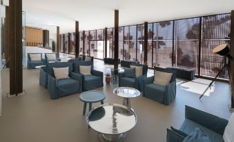 a large , modern living room with blue couches and chairs arranged around a coffee table at Masseria Amastuola Wine Resort