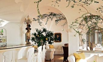 a living room with a large arched ceiling and white furniture , decorated with plants and flowers at Covo dei Saraceni