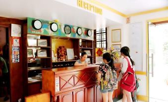 a group of people standing in line at a reception desk , with the clock displayed above them at Cay Thong Hotel