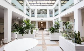 a modern , spacious lobby with white marble floors and columns , featuring several potted plants and benches at Hotel Monteverde