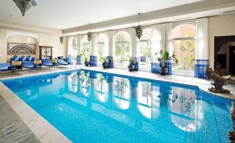 a large swimming pool with blue water is surrounded by white walls and has several lounge chairs in front of windows at Kasbah Tamadot