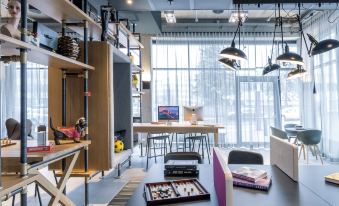 a room with a dining table and chairs , as well as various items such as books , cups , and a computer at Moxy Edinburgh Airport