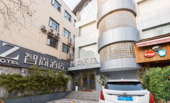 The front entrance of a hotel is shown, with an outside view and parked cars in the adjacent parking lot at Zhotels (Shanghai West Nanjing Road Westgate Mall)