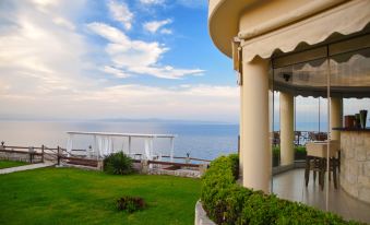 a balcony overlooking a lush green lawn and the ocean , with a view of the water at Blue Bay Halkidiki