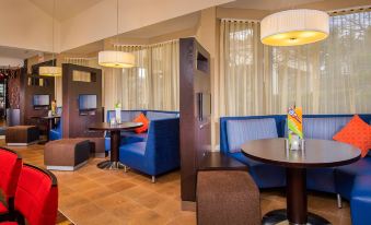 a modern , well - lit hotel lobby with blue couches and chairs , as well as tables and television at Courtyard Manassas Battlefield Park