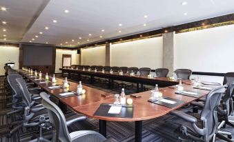 a large conference room with a long table , chairs , and various items on the table at Novotel Montréal Centre