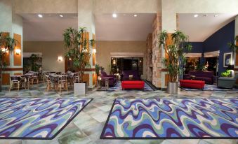 a spacious hotel lobby with high ceilings , multiple potted plants , and several couches arranged around the area at Holiday Inn Rock Springs