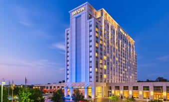 a modern hotel building with the westin hotel sign illuminated against a blue sky at The Westin Chicago North Shore