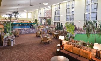 an indoor courtyard with a large pool , surrounded by tables and chairs , creating a relaxing atmosphere at Ramada Plaza by Wyndham Sheridan Hotel & Convention Center