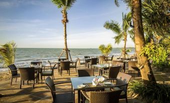 an outdoor dining area at a resort , with tables and chairs set up for guests to enjoy a meal at Robinson Khao Lak