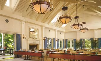 a large , well - lit room with multiple dining tables and chairs , as well as a fireplace in the background at Montage Palmetto Bluff