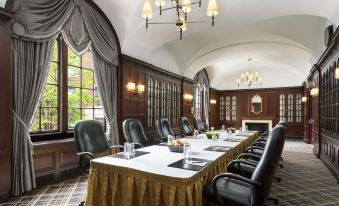 a large conference room with a long table , multiple chairs , and multiple potted plants , under a chandelier at Hilton Boston Park Plaza