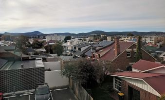 a view of a city street with buildings and mountains in the background , taken from an elevated position at Prince of Wales Hotel