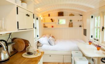 a cozy bedroom with a white bed , wooden furniture , and a bookshelf filled with books at The Snug