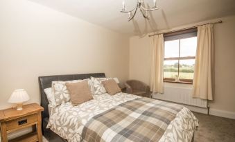 a cozy bedroom with a large bed , a couch , and a tv . the room is well - lit and appears to be spacious at Stanley Lodge Farmhouse