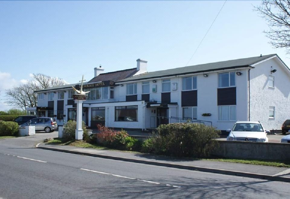 a row of white buildings with black shutters and a car parked in front of one at The Anchorage Hotel