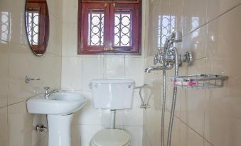 a small bathroom with white walls , tile flooring , and a window that offers natural light at Collin Hotel