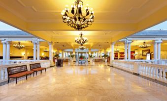 a large , well - lit hotel lobby with marble floors , high ceilings , and a large chandelier hanging from the ceiling at Grand Palladium Lady Hamilton Resort & Spa - All Inclusive
