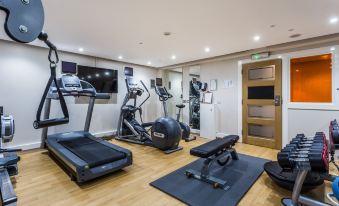 a well - equipped gym with various exercise equipment , including treadmills and weight machines , along with mats and mirrors at Holiday Inn Sittingbourne