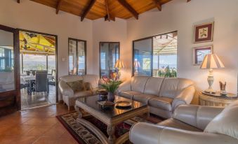 a spacious living room with two leather couches and a coffee table in the center , surrounded by windows that allow natural light to fill the space at Barons Resort