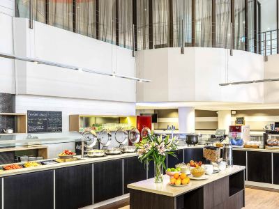 a modern cafeteria with multiple dining tables , including one for breakfast and another for a meal at Ibis Melbourne Hotel and Apartments