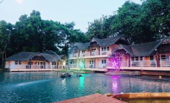 a resort with multiple buildings , including a hotel and a restaurant , situated on the shore of a large body of water at Baanrai Riverkkwai Resort