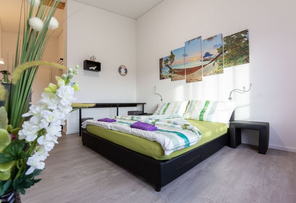 a modern bedroom with a large bed , black headboard , and colorful bedding , as well as a wooden floor at Beachin - Sport, Events, Hotel, Restaurant, Bar