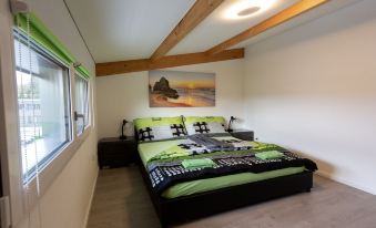 a cozy bedroom with a large bed , wooden beams , and a painting on the wall at Beachin - Sport, Events, Hotel, Restaurant, Bar