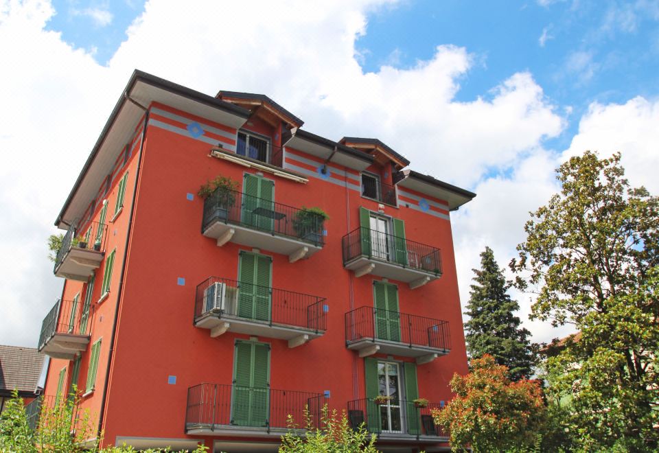 a large , red apartment building with green balconies and windows , situated in a residential area at Franco