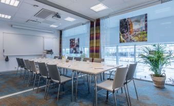 a conference room with a long table and chairs , colorful curtains , and large windows near a window at Radisson Blu Hotel Uppsala