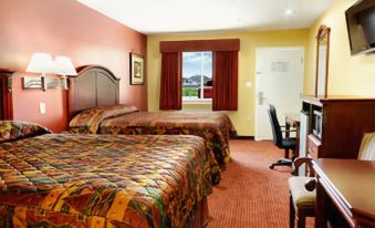 a hotel room with two beds , a desk , and a window , all decorated in a cozy style at La Quinta Inn & Suites by Wyndham Houston Channelview