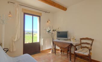 a bedroom with a bed , desk , and computer is shown with a view of the outdoors through a window at La Fabrique