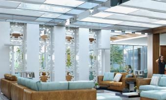 a modern living room with white columns , brown leather couches , and wooden chairs , under a large skylight at Burgu Arjaan by Rotana