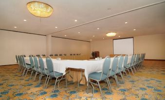 a conference room with a large table surrounded by chairs , a projector screen , and colorful carpet at Best Western Plus Burley Inn Convention Center